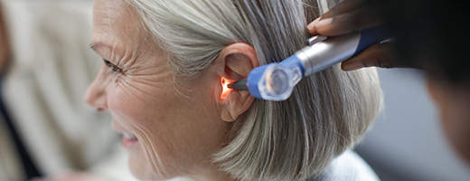 Close-up image of senior woman getting her ear examined by a hearing care professional